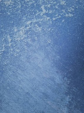 Bokeh etkisi ve karakteristik kaba gözenekli dokuya sahip dekoratif bir duvarın, klasik mavi arka planda soyut koyu ve açık renkli noktaların yakın çekimi.