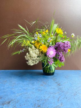 Kahverengi bir arka planda dekoratif vazoda büyük bir buket parlak yabani çiçek. Boş alan. Defocus açık arkaplan.