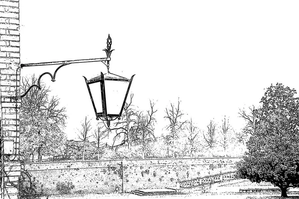 A vintage style street wall mounted lamp hanging on a building near the park in black and white lithography style