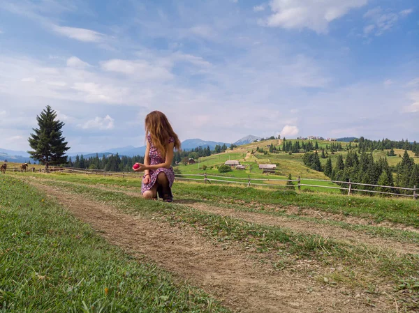 Fiatal vörös hajú nő ül a nyomvonal a hegyek völgyében alatt meleg napsütéses nyári napon — Stock Fotó