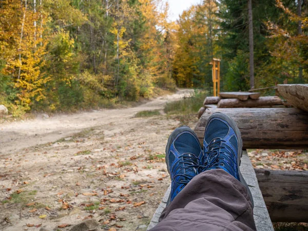Clouse-up um homem pés em botas azuis enquanto descansa no banco de madeira Fotos De Bancos De Imagens