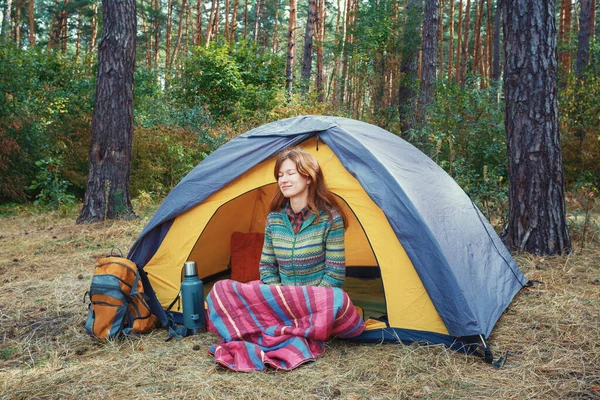 Sarı gri çadırda oturan, sonbahar ormanlarında doğanın tadını çıkaran, kızıl saçlı genç bir kız.. — Stok fotoğraf