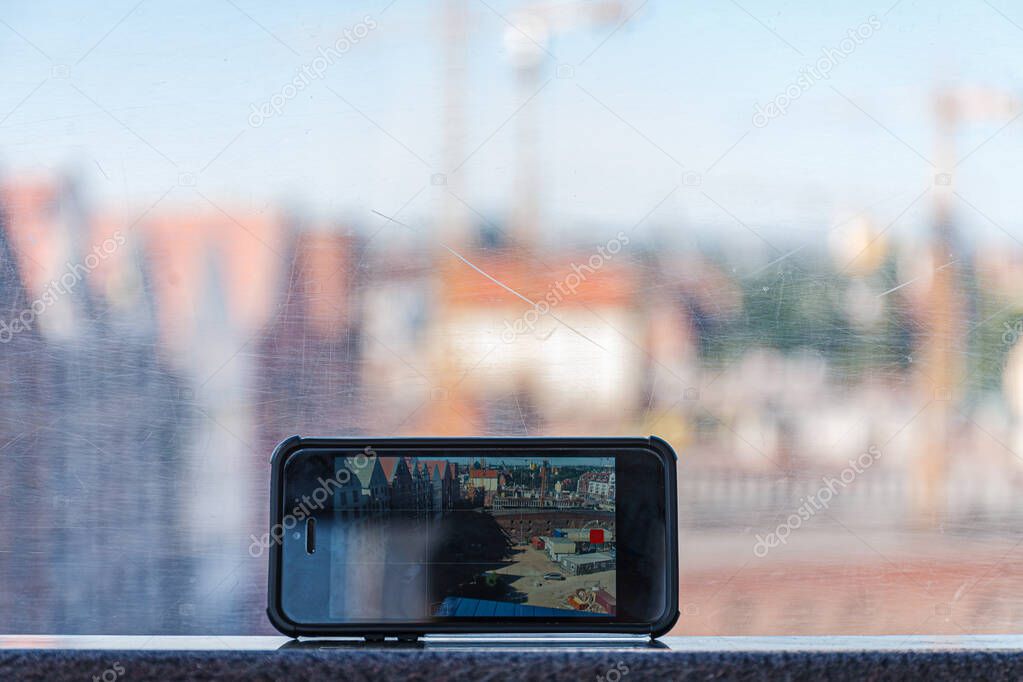 View through old scratched glass window. Blurred cityscape background