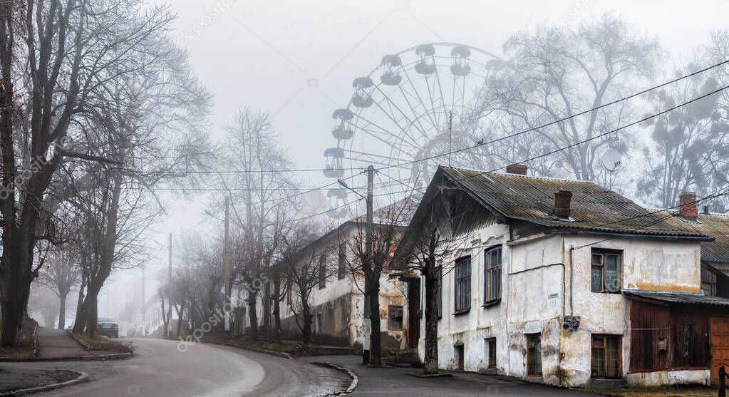 View of misty street and ferris wheel and old white buildings