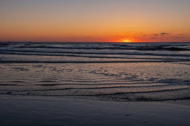 Karadeniz 'de gün batımında muhteşem bir manzara ve üzerinde muhteşem bir güneş ışığı olan turuncu gökyüzü arka plan olarak sakin dalgaların üzerinde. Sahilde muhteşem bir yaz gün batımı manzarası. Rus doğası, Soçi.