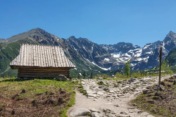 Ηλιόλουστο ξύλινο σπίτι στο δρόμο στα βουνά — Φωτογραφία Αρχείου