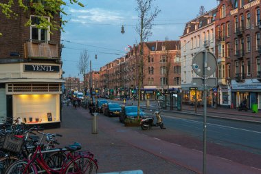 Bir grup insan Amsterdam caddesinde işe bisikletle gidiyor.