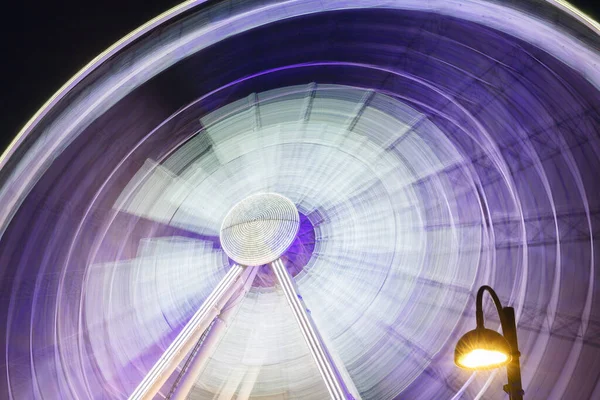 Fechar girando roda gigante roxa branca em movimento wih lâmpada à noite — Fotografia de Stock