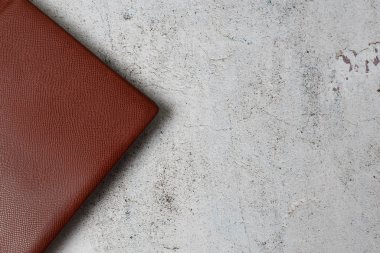 Gri beton arka planda kırmızı deri not defterine yakın plan.