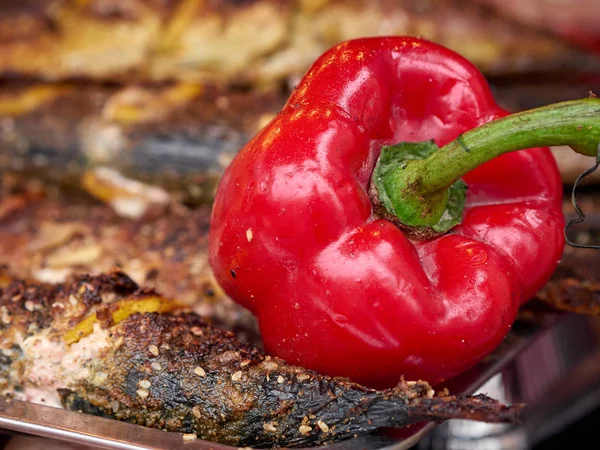 Colorful roasted red pepper and grilled or fried fish on trays at street food festival — Stock Photo, Image