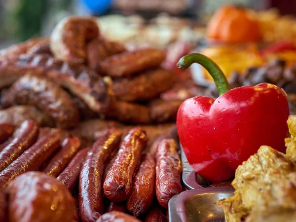 Kırmızı ızgara sosis yığını ve sokak yemekleri festivalinde tepside kızarmış kırmızı biber. — Stok fotoğraf