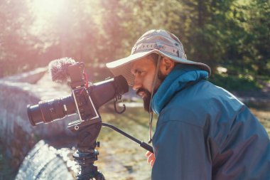 Seyahat fotoğrafçısı kamerayla fotoğraf çekiyor, sahne arkasında çekim yapıyor.