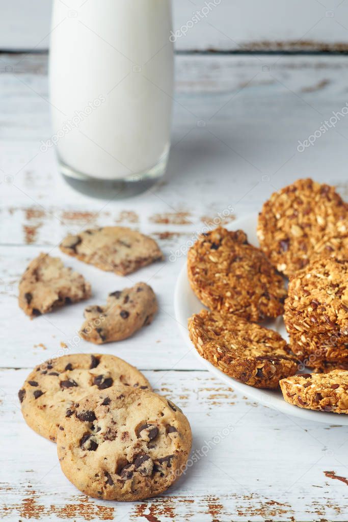 Granola cookies and glass cup of milk on wooden surface.