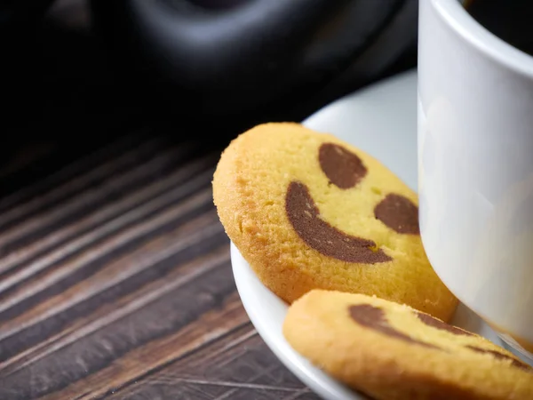 Stor vit kaffekopp, svart hörlurar och gula kakor med glada leenden — Stockfoto