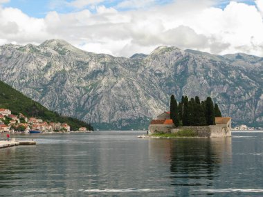 Gemiden Perast 'e panoramik manzara, Aziz George Benedictine manastırı, Kotor körfezi ve çevresindeki dağlar, beyaz bulutlu mavi gökyüzü, Karadağ