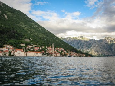 gemiden Perast, Kotor körfezine ve çevresindeki dağlara panoramik manzara, beyaz bulutlu mavi gökyüzü, Karadağ