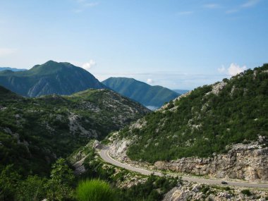 Güneşli bir sabahta dağ yolu, mavi gökyüzü, beyaz bulutlar, dağlar, Karadağ