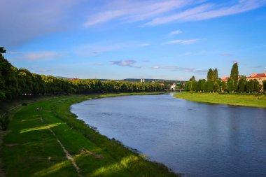 Nehir ve toprak, mavi gökyüzü, beyaz bulutlar, ıhlamur ağaçları, Uzhhorod, Ukrayna