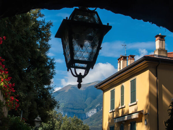 Old lantern on a background of mountains and blue sky, Bellagio, Italy