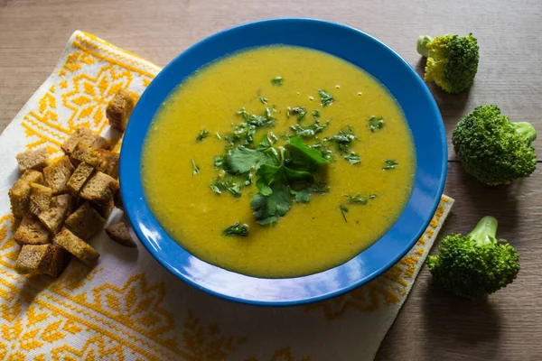 Brokoli kremalı çorba, kızarmış ekmek, maydanoz ve dereotu mavi tabakta.