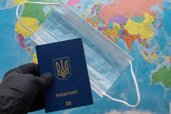 gloved hand, passport and medical mask on the background of the map, symbolizing quarantine due to the coronavirus pandemic
