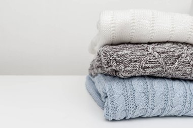 Bir yığın konforlu ev yapımı örgü örülmüş kazak pastel renkler, çamaşır ve çamaşır konsepti. Beyaz arkaplan, alanı kopyala