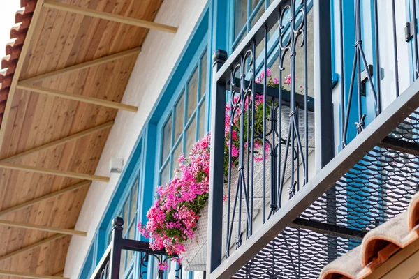 Maison italienne avec des cadres de fenêtre en bois bleu et balcon avec des fleurs en pot, géraniums — Photo