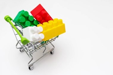 Alışveriş arabasında bir sürü renkli oyuncak plastik tuğla, beyaz arka planda tramvay, satış ve alışveriş konsepti, kopyalama alanı