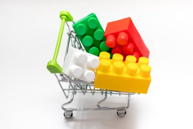 Alışveriş arabasında bir sürü renkli oyuncak plastik tuğla, tramvay, satış ve alışveriş konsepti