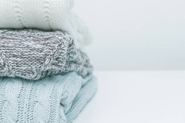 Bir yığın konforlu ev yapımı örgü örülmüş kazak pastel renkler, çamaşır ve çamaşır konsepti. Beyaz arkaplan, alanı kopyala