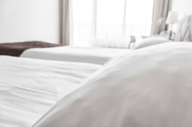 Beyaz çarşaflı ve yastıklı bir yatak bir otel dairesine yakın.