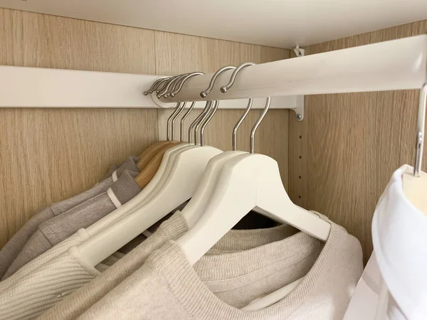 Beige woman sweaters hanging on rail in the wardrobe — Stock Photo, Image