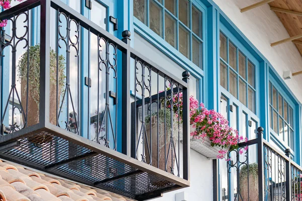 Maison italienne avec des cadres de fenêtre en bois bleu et balcon avec des fleurs en pot, géraniums — Photo