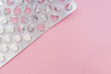 Gerginliği, asabiyeti ve uykusuzluğu önlemek için pembe arka planda yatıştırıcı haplar içeren yarı kullanılmış bir su toplayıcısı paketi.