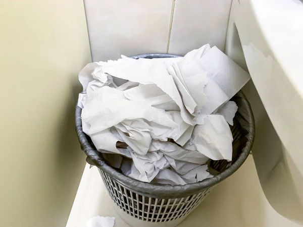 Cubo de basura desbordante, cubo de basura lleno de papel higiénico usado cerca del inodoro en un baño público —  Fotos de Stock