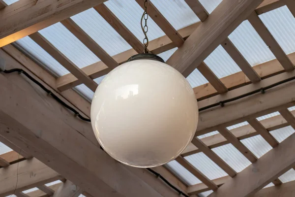 Una lampada da soffitto bianca a sfera appesa al patio esterno, di giorno — Foto Stock