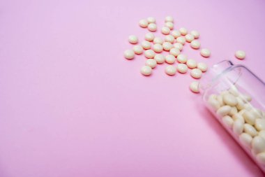 Tablet hapları insanda tedavi için cam şişe parazit antelmintik antiparazit iplik kurdu ya da kurt sineği solucanına karşı etkili pembemsi tenya bağırsak kurdu tenya da pembe arka plan kopyalama uzayı.