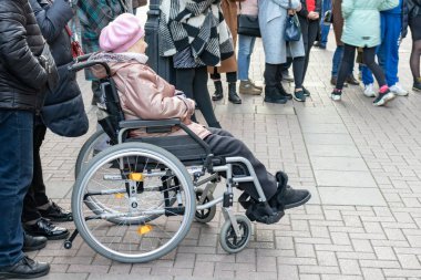 Moskova, Rusya - 19 Ekim 2019: Tekerlekli sandalyedeki yaşlı engelli bir kadın sokak müzisyenlerini izliyor ve dinliyor
