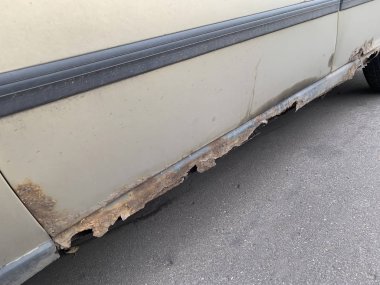 Rusty car threshold with holes in metal, corrosion on an old automobile