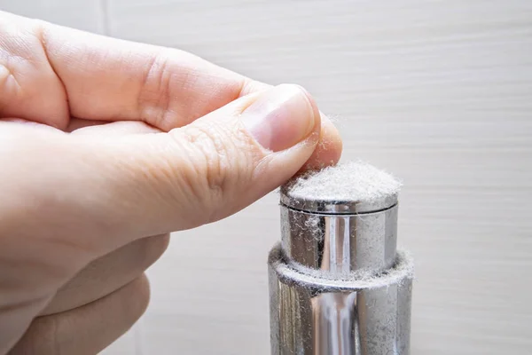 Dedos sosteniendo un pedazo de polvo de cromado en el cuarto de baño, el concepto de casa polvorienta — Foto de Stock