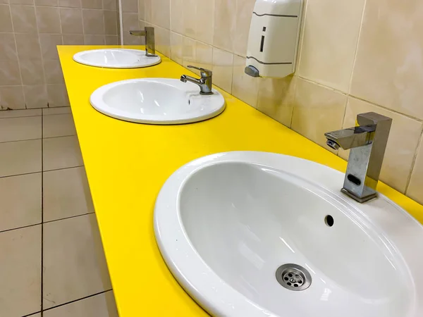 Fila de lavabo moderno amarillo en un baño público —  Fotos de Stock