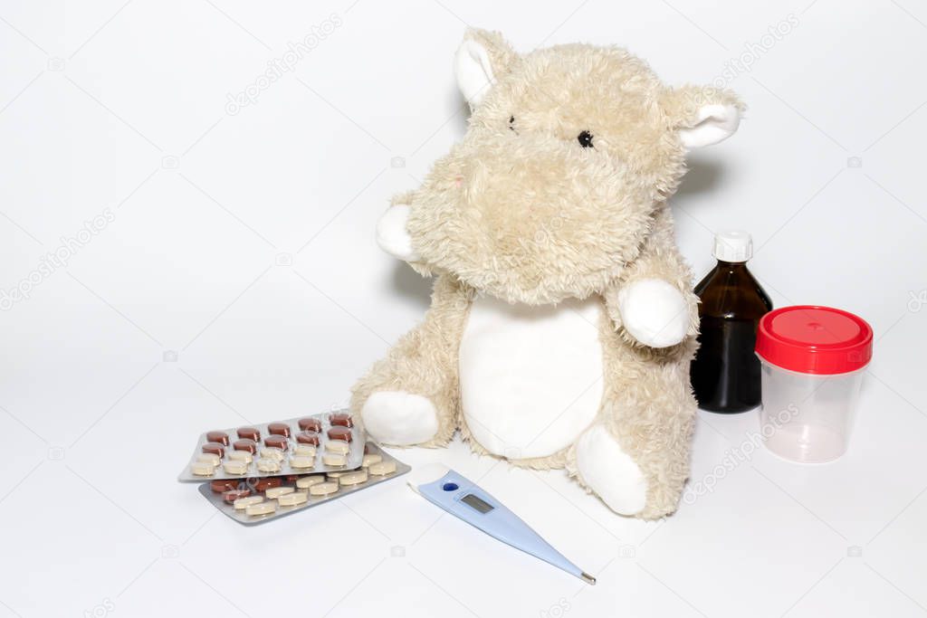 Childhood diseases concept, a teddy hippo with means for treatment fever, pain flu cough and sore throat, copy space