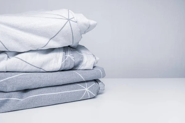 Uma pilha de aconchegante têxteis caseiros em tons de roupa de cama cinza, roupa de cama com espaço de cópia — Fotografia de Stock