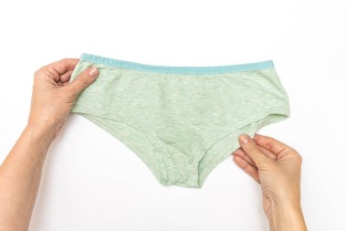 Hap alan bir kadın, elinde mavi haplar, kapsüller ve beyaz masada bir bardak su tutan bir kadın eli.