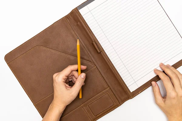 Les mains de la femme tenant un cahier et un crayon jaune et l'écriture, fermer l'espace de copie vue du dessus — Photo