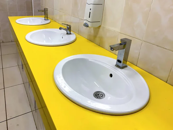 Rad av gul modern tvättställ i en offentlig toalett — Stockfoto