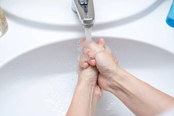 Mujer lavándose las manos bajo el grifo con agua, higiene y concepto de perfilería — Foto de Stock