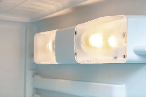 Una luz dentro de la nevera, refrigerador de cerca, una lámpara que la respuesta a encender cuando la puerta está abierta, mantenimiento del concepto de electrodomésticos, cambiar la lámpara en un congelador —  Fotos de Stock