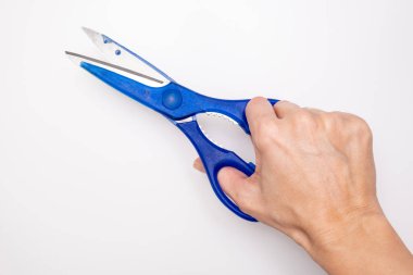 Blue scissors in a hand close up on white background