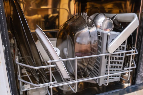 Open overloaded dishwasher with different dishes and kitchen utensils — 스톡 사진